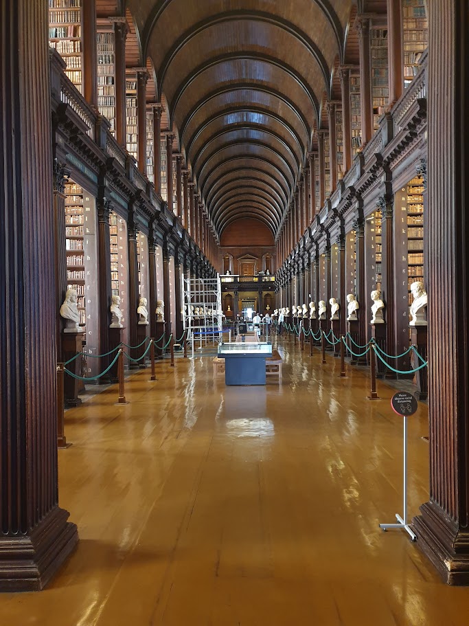 Photo of the Long Room in Trinity College, Dublin. Many, many tall bookshelves recede into the distance.